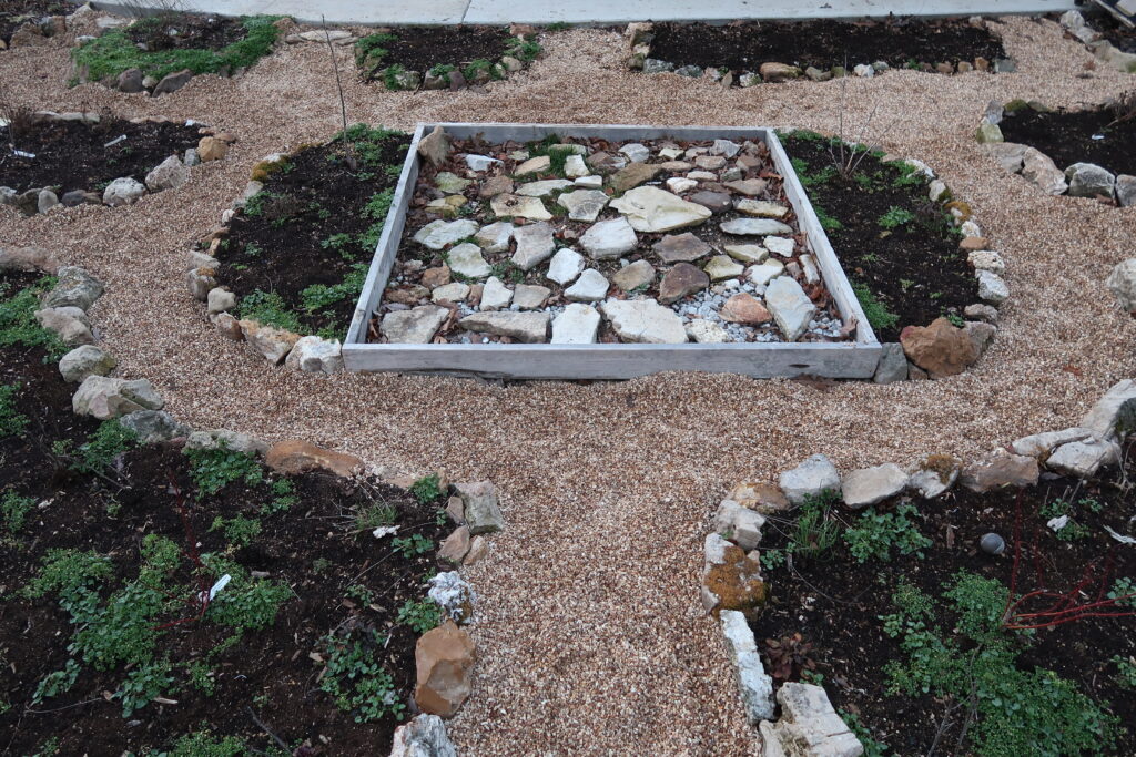 garden beds lined with rocks, square form in the middle with flat rocks, pea gravel walkways